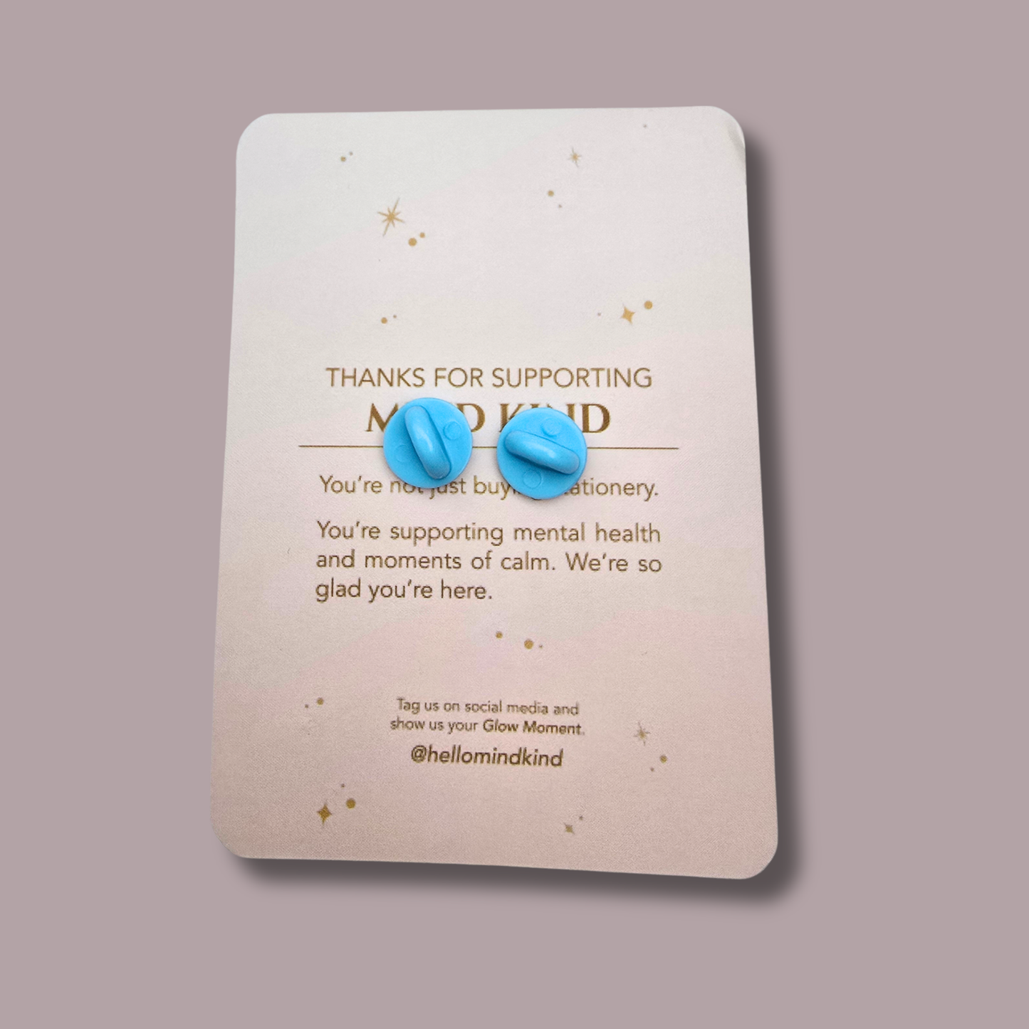 The backing card reads 'THANKS FOR SUPPORTING MIND KIND' and features a soft drop shadow against a solid muted mauve background.