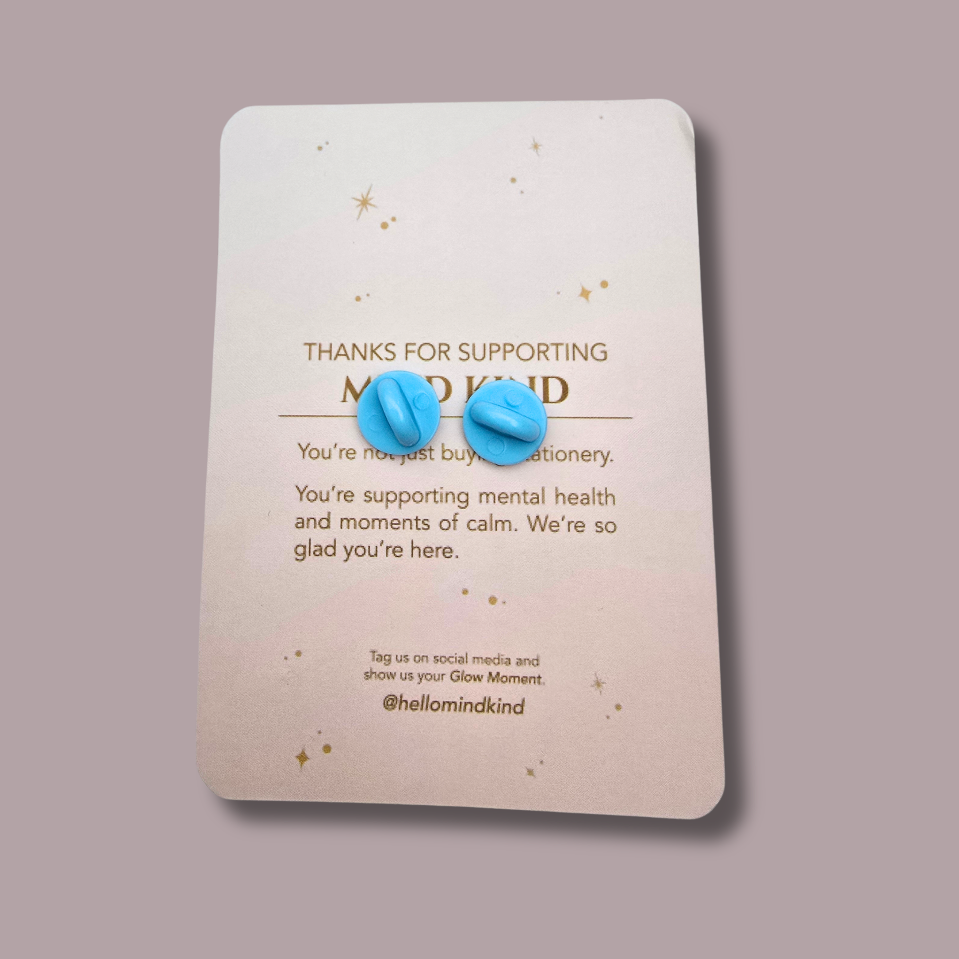 The backing card reads 'THANKS FOR SUPPORTING MIND KIND' and features a soft drop shadow against a solid muted mauve background.
